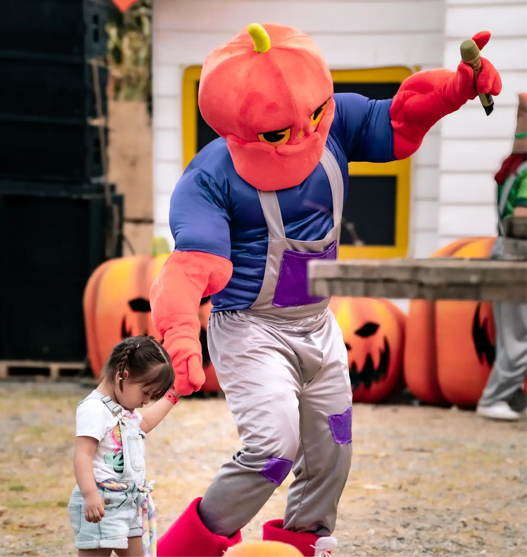 Un personaje con cabeza de calabaza baila con una niña