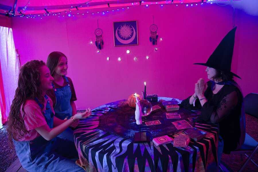 Dos mujeres con una bruja practicando Tarot